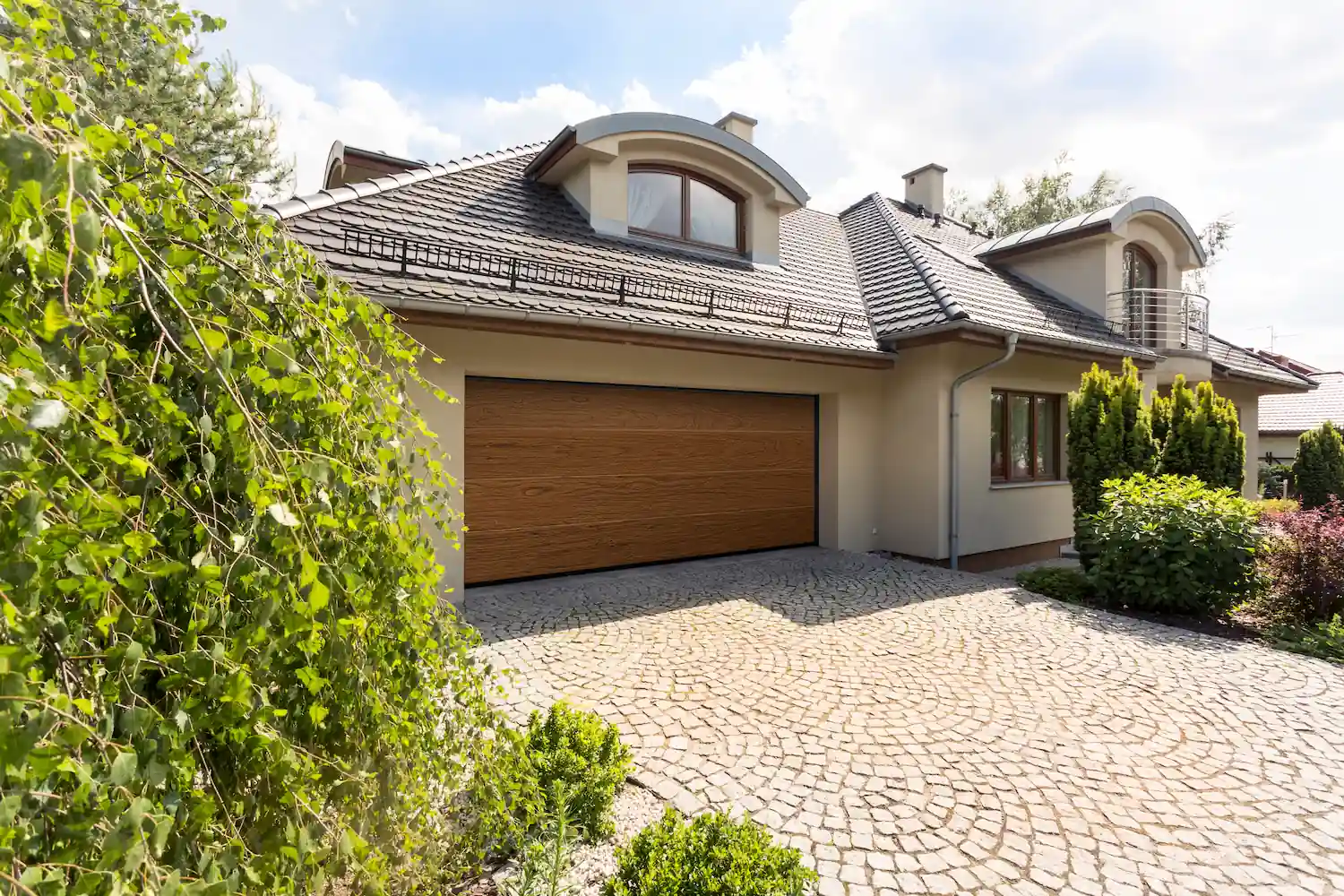 Porte de garage sectionnelle Normstahl imitation bois installée sur une villa à toit en tuiles.
