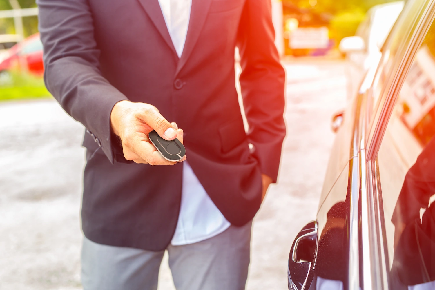 Homme en costume actionnant une télécommande de porte de garage Normstahl à côté d'une voiture.
