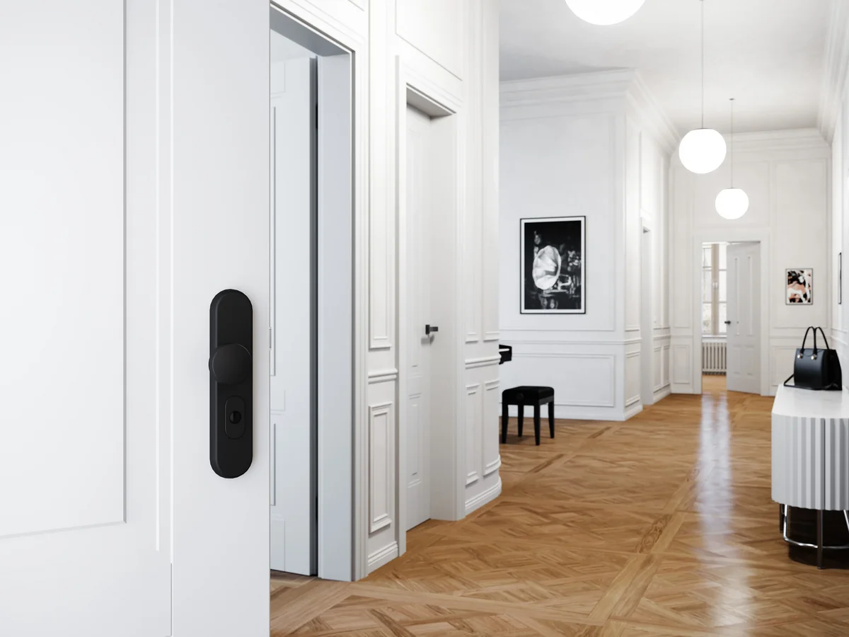 Porte coulissante blanche à panneaux moulurés dans un couloir haussmannien au parquet en chêne à motifs, avec suspensions boules.