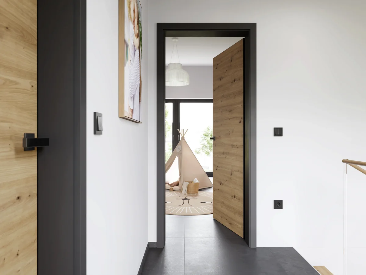 Porte intérieure en bois clair grand format ouverte sur une chambre d'enfant avec tipi et tapis rond, dans un couloir au sol en béton ciré.